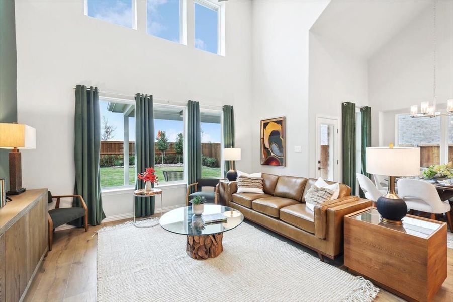 Living area with light wood-type flooring, hanging lights, and a high ceiling