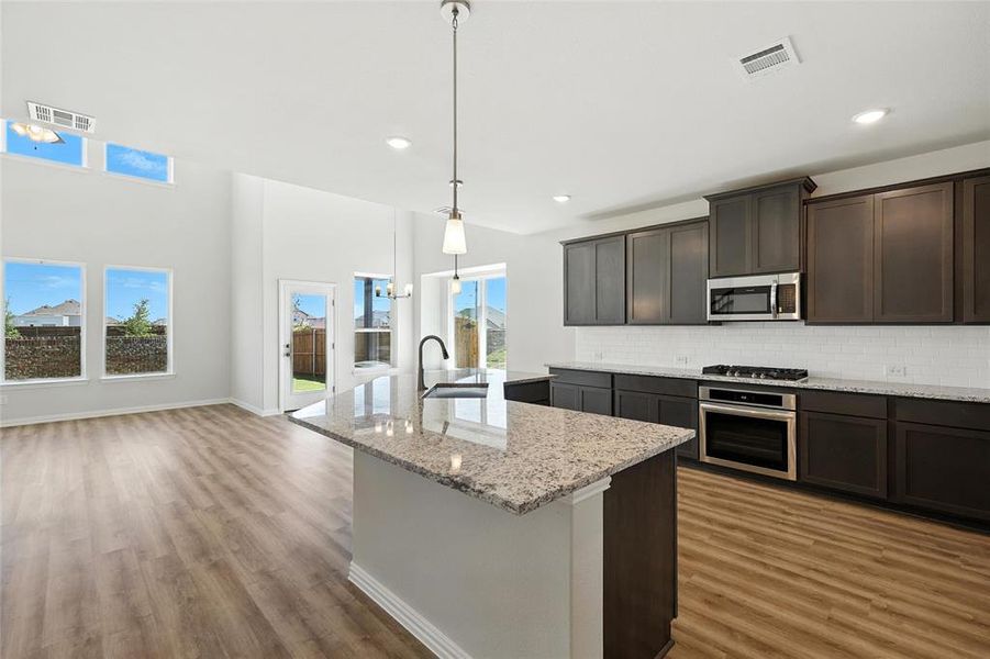 Kitchen with appliances with stainless steel finishes, light wood finished floors, decorative backsplash, a center island with sink, and recessed lighting Kitchen with appliances with stainless steel finishes, light wood finished floors, decorative backsplash, a center island with sink, and recessed lighting