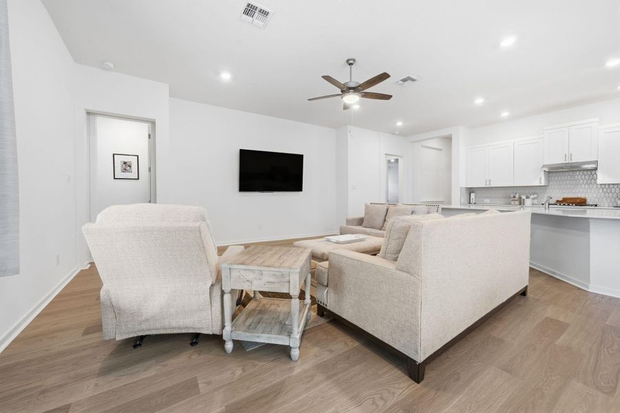 Living area with ceiling fan, light wood-style floors, and recessed lighting