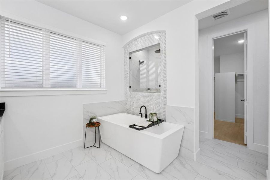 Full bath featuring a freestanding tub, a walk in closet, light marble finish flooring, and recessed lighting Full bath featuring a freestanding tub, a walk in closet, light marble finish flooring, and recessed lighting