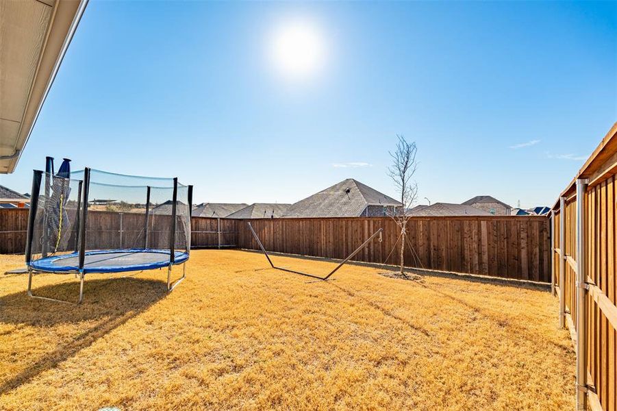 View of yard with a trampoline and a fenced backyard