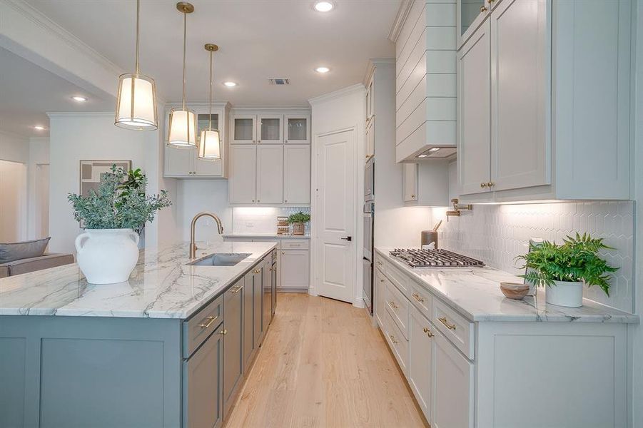 Kitchen with custom cabinets to the ceiling, leathered Quartzite counters, tile backsplash, decorative lighting, ample storage, soft close doors and drawers, and gas cooktop. Kitchen with custom cabinets to the ceiling, leathered Quartzite counters, tile backsplash, decorative lighting, ample storage, soft close doors and drawers, and gas cooktop.