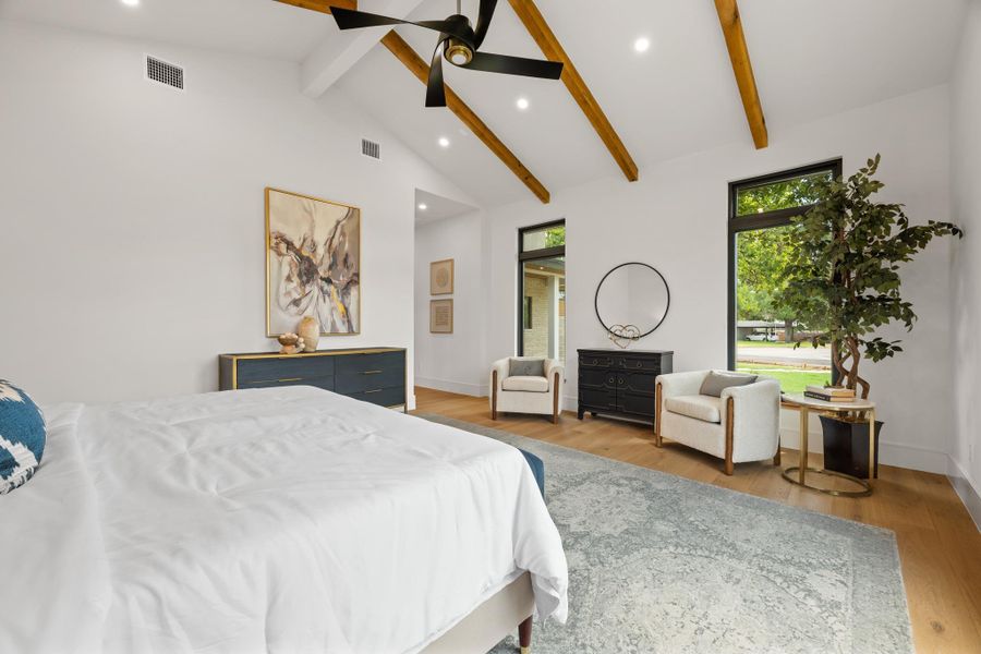 Exposed wood beams and vaulted ceilings elevate this modern bedroom with warm hardwood floors.