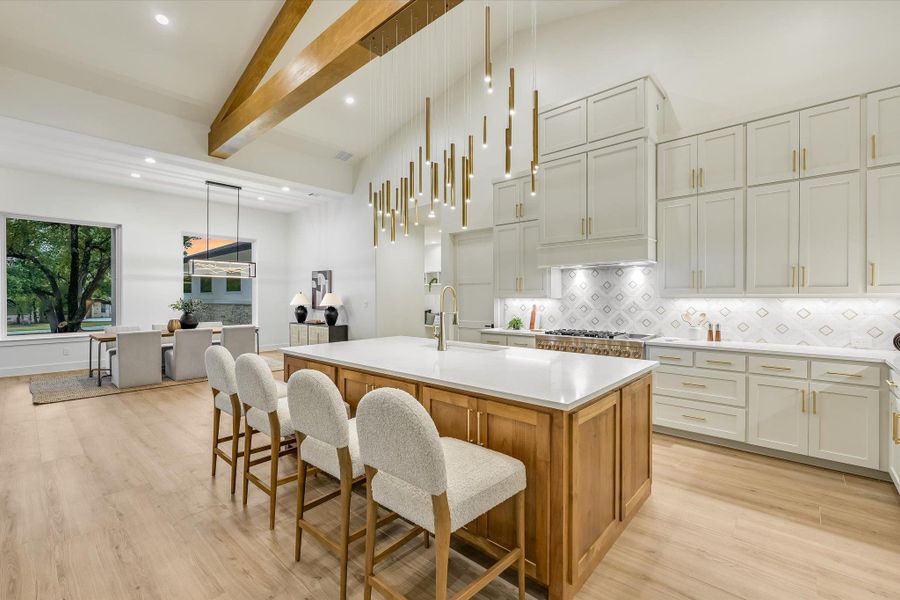 Kitchen featuring a kitchen island with sink, light wood-style floors, a kitchen breakfast bar, decorative light fixtures, and dual tone cabinets