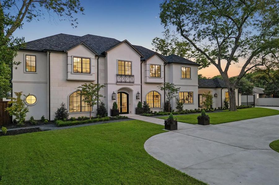 View of front of property featuring a circle drive and a lush lawn.