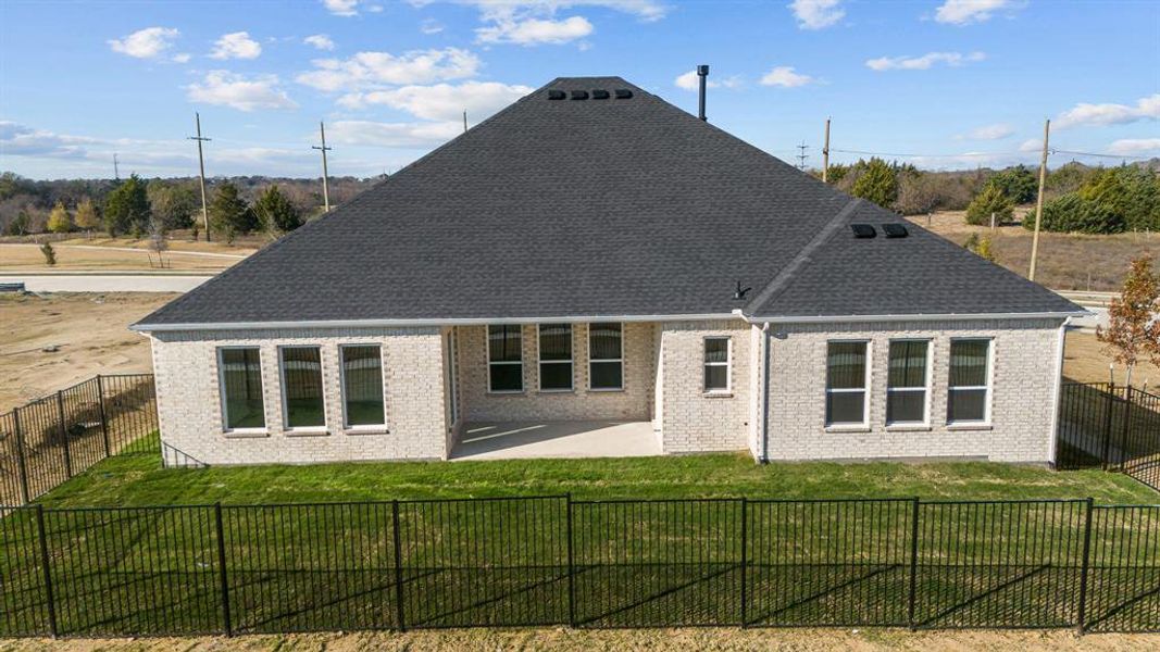 Rear view of property with brick siding, a fenced backyard, a shingled roof, and a patio