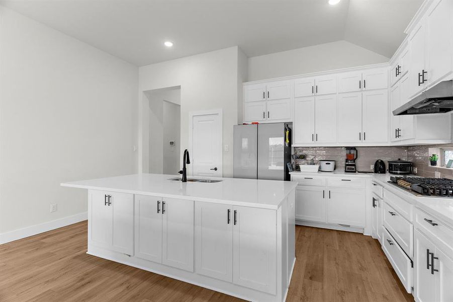 Kitchen featuring a sink, stainless steel appliances, tasteful backsplash, an island with sink, and lofted ceiling Kitchen featuring a sink, stainless steel appliances, tasteful backsplash, an island with sink, and lofted ceiling