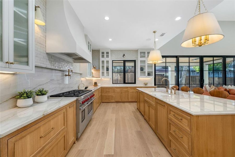 Spacious kitchen with light wood-finish flooring, white countertops, and natural wood cabinetry
