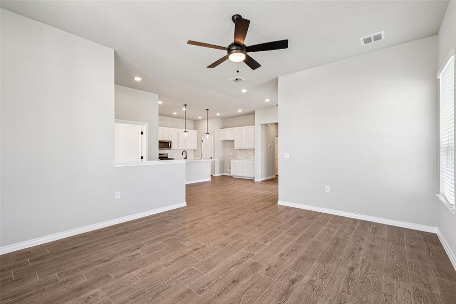 Unfurnished living room with ceiling fan, wood finished floors, baseboards, a sink, and recessed lighting Unfurnished living room with ceiling fan, wood finished floors, baseboards, a sink, and recessed lighting