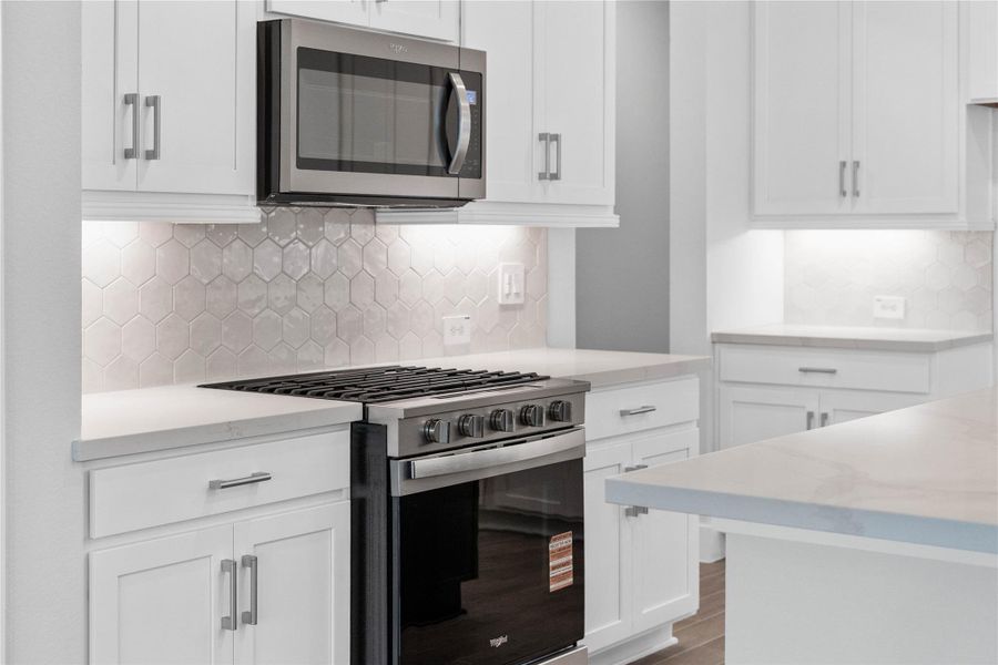 Enjoy cooking with a full suite of stainless steel appliances, including a gas range, set against a bright, modern backdrop.