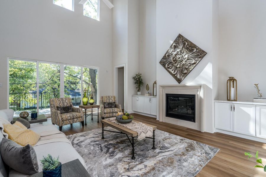 Spacious living area with high ceilings, tall windows, built-in cabinetry, and a statement fireplace. Spacious living area with high ceilings, tall windows, built-in cabinetry, and a statement fireplace.