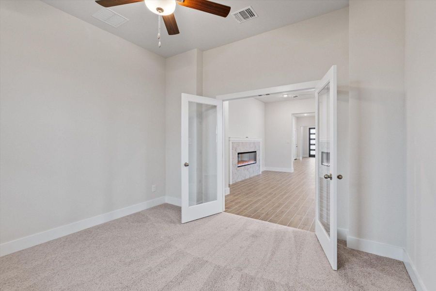 French doors open into a versatile space featuring a fireplace, blending comfort and style.