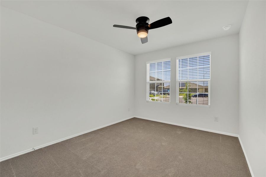 A well-lit bedroom features plush carpeting and multiple windows.