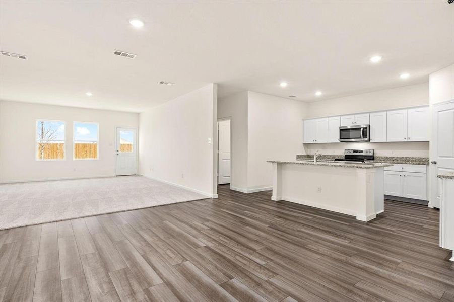 Kitchen featuring white cabinets, open floor plan, recessed lighting, an island with sink, and appliances with stainless steel finishes Kitchen featuring white cabinets, open floor plan, recessed lighting, an island with sink, and appliances with stainless steel finishes