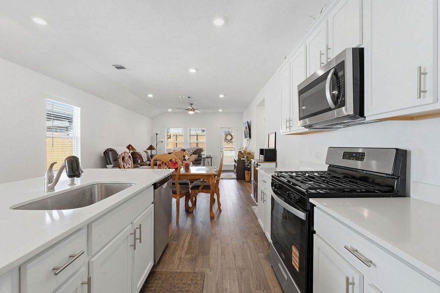 Kitchen featuring stainless steel appliances, white cabinets, healthy amount of natural light, recessed lighting, and lofted ceiling