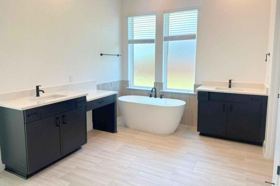 Full bathroom featuring a freestanding bath, two vanities, tile walls, and wainscoting Full bathroom featuring a freestanding bath, two vanities, tile walls, and wainscoting