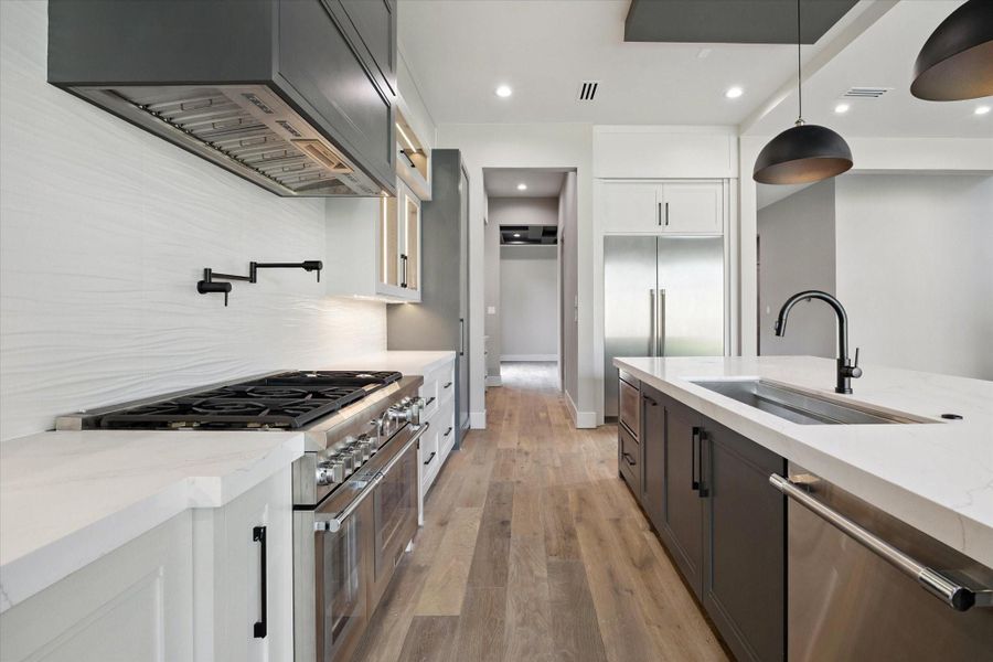 Thermador appliances elevate the space with a professional gas range featuring double ovens, a sleek vent hood, and a convenient pot filler. The kitchen is further equipped with a dishwasher and microwave, blending performance and luxury for the ultimate cooking experience.