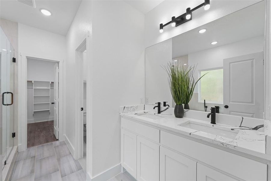 Dual vanity with integrated rectangular sinks, stone-finish countertops, and matte black fixtures Dual vanity with integrated rectangular sinks, stone-finish countertops, and matte black fixtures