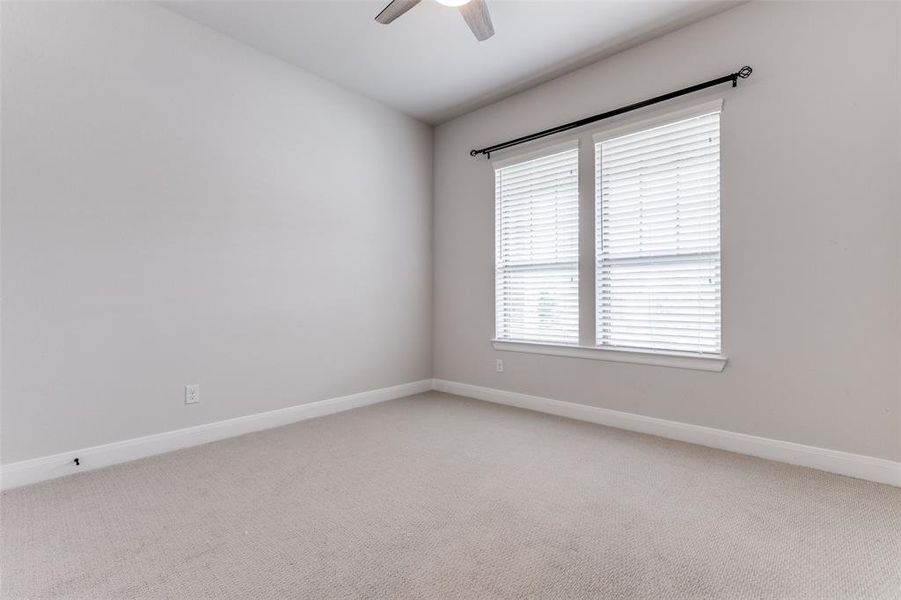 Spare room with light carpet, a ceiling fan, and baseboards