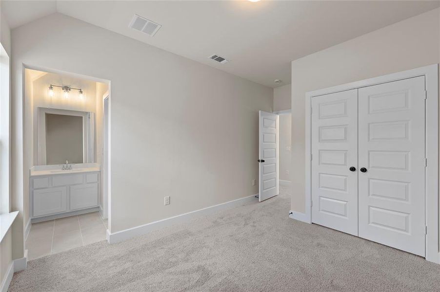 Unfurnished bedroom featuring light colored carpet, a closet, and ensuite bathroom Unfurnished bedroom featuring light colored carpet, a closet, and ensuite bathroom