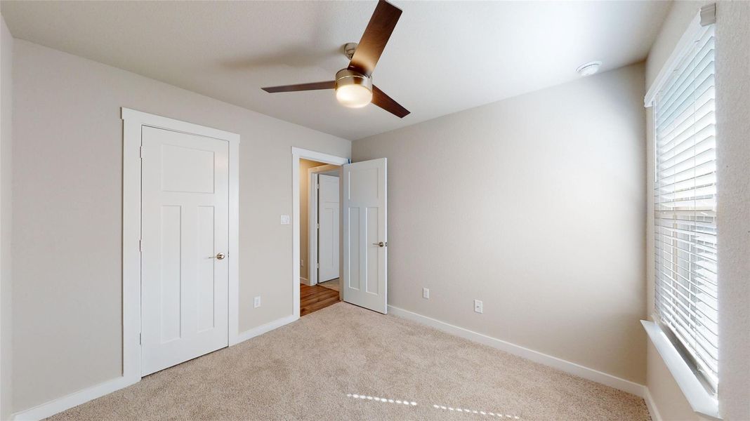 A well-proportioned room with soft carpet flooring and a modern ceiling fan, offering a comfortable personal retreat. A well-proportioned room with soft carpet flooring and a modern ceiling fan, offering a comfortable personal retreat.