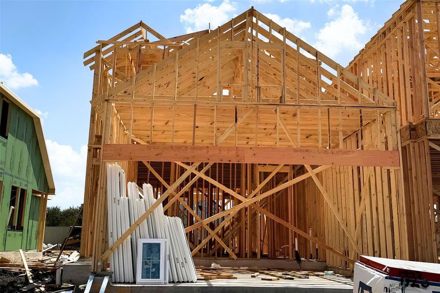 A new residential structure takes shape with sturdy wood framing against a clear blue sky.