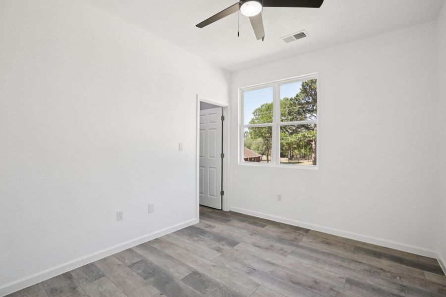 Bedroom 2 with ceiling fan and light wood-type laminate flooring