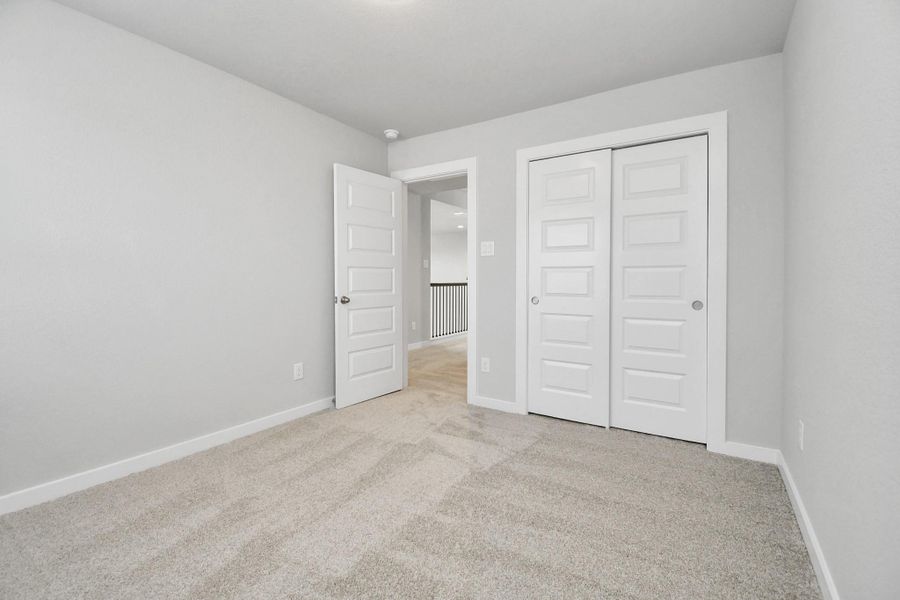 Secondary bedroom features plush carpeting, large windows that let in plenty of natural light, bright paint, and spacious closets. Sample photo of completed home with similar floor plan. Actual colors and selections may vary.