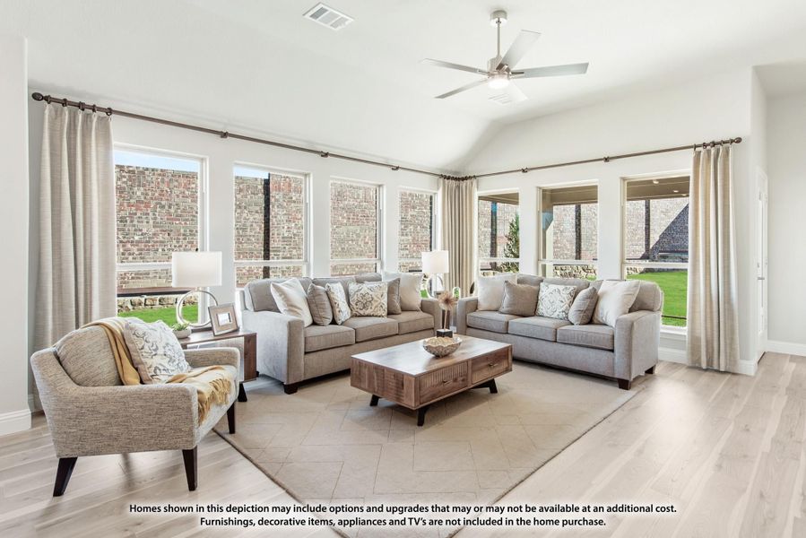 Bright living room with vaulted ceiling, ceiling fan, gray sofas, and large windows with neutral drapes Bright living room with vaulted ceiling, ceiling fan, gray sofas, and large windows with neutral drapes