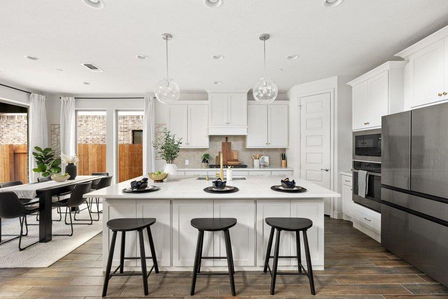 White cabinetry and quartz countertops elevate this sleek, open-concept kitchen with integrated dining.