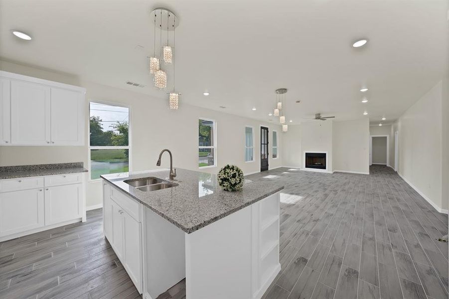 Kitchen featuring light wood-style flooring, a fireplace, white cabinets, recessed lighting, and open shelves