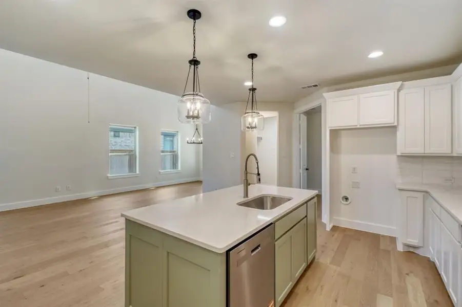 Kitchen featuring an island with sink, light wood-type flooring, dishwasher, light stone counters, and open floor plan Kitchen featuring an island with sink, light wood-type flooring, dishwasher, light stone counters, and open floor plan