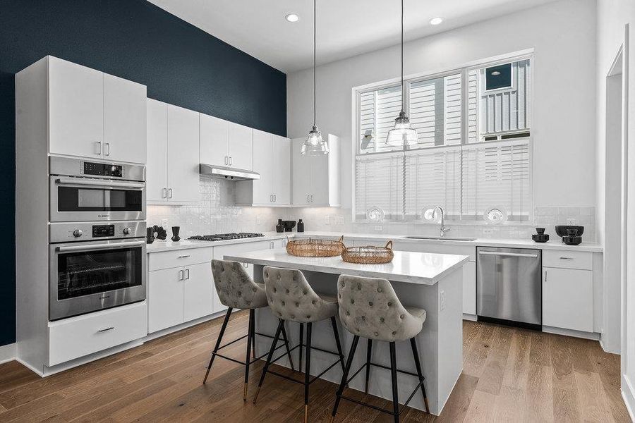 Kitchen with white cabinetry, a kitchen bar, stainless steel appliances, pendant lighting, and dark wood-type flooring