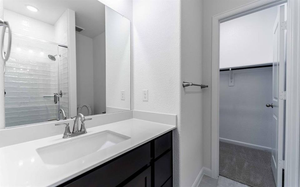 Bathroom vanity featuring a single integrated sink, a dark wood-finish cabinet with drawer storage, and a large mirror