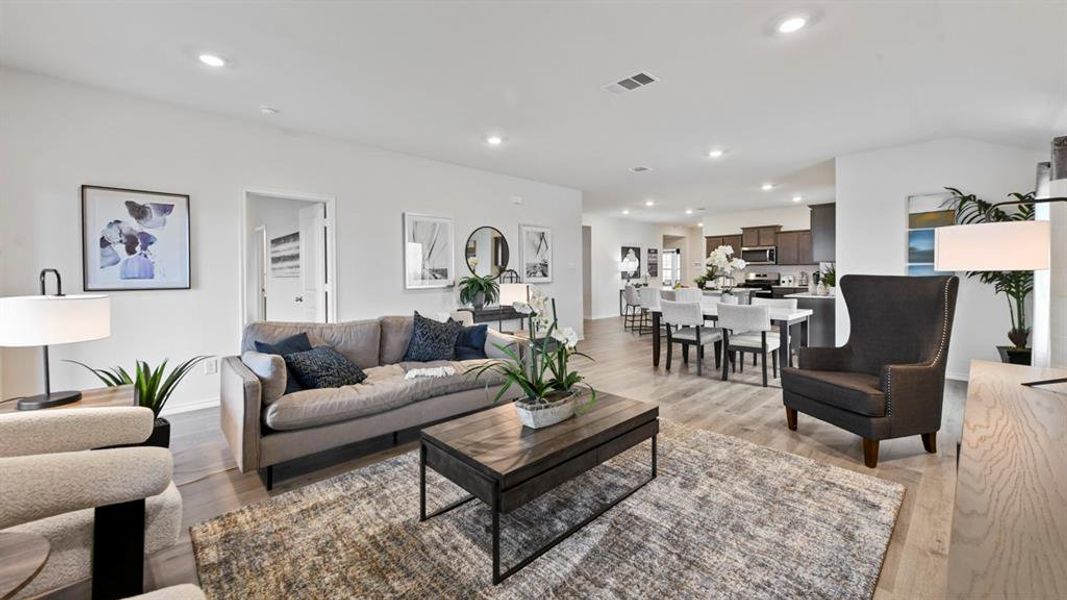 Open-concept living space featuring wood-finish flooring, recessed lighting, and white wall finishes Open-concept living space featuring wood-finish flooring, recessed lighting, and white wall finishes