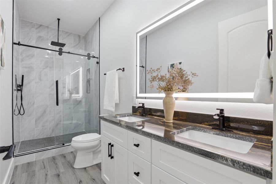 Modern bathroom featuring a double vanity with stone countertops, undermount sinks, and matte black fixtures