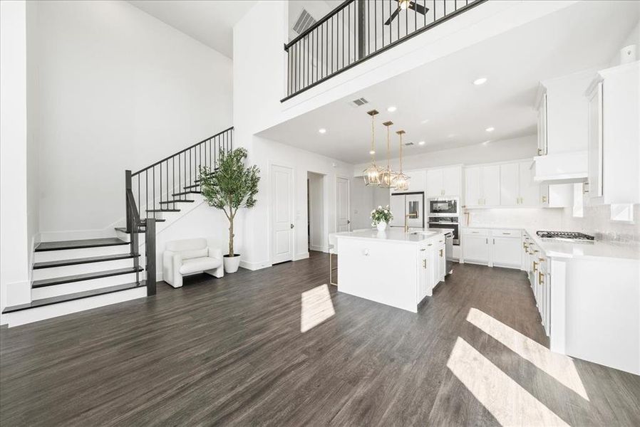 Kitchen with dark wood-style floors, white cabinetry, stainless steel appliances, and light countertops