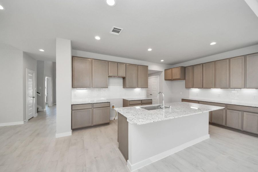 The kitchen is a culinary haven, featuring granite countertops, a tile backsplash, stainless steel appliances, 42” upper cabinets, and undercabinet lighting. Sample photo of completed home with similar floor plan. Actual colors and selections may vary.