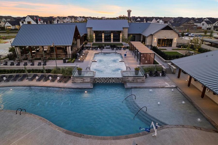 Pool at dusk with a patio area, a community pool, and a residential view Pool at dusk with a patio area, a community pool, and a residential view