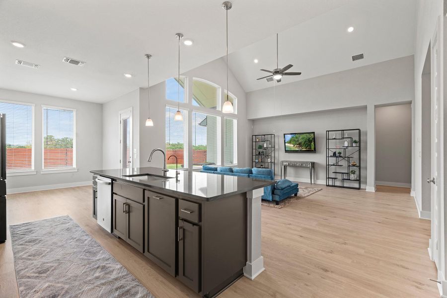 Kitchen featuring open floor plan, decorative light fixtures, light wood finished floors, a kitchen island with sink, and a ceiling fan Kitchen featuring open floor plan, decorative light fixtures, light wood finished floors, a kitchen island with sink, and a ceiling fan