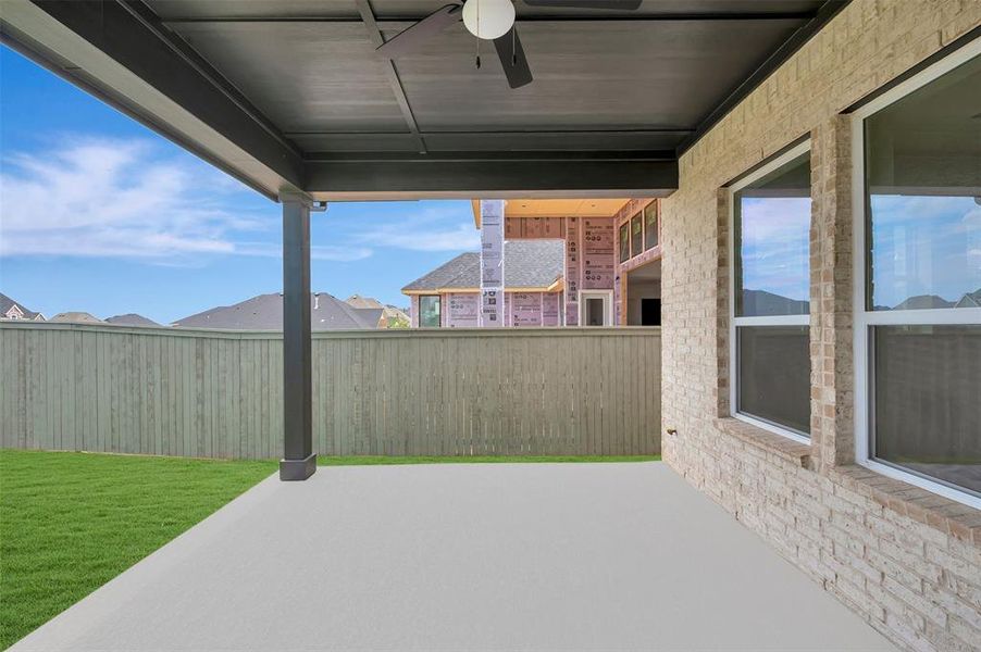 Covered outdoor patio featuring a ceiling fan with integrated lighting, a concrete slab, and a light-toned brick exterior