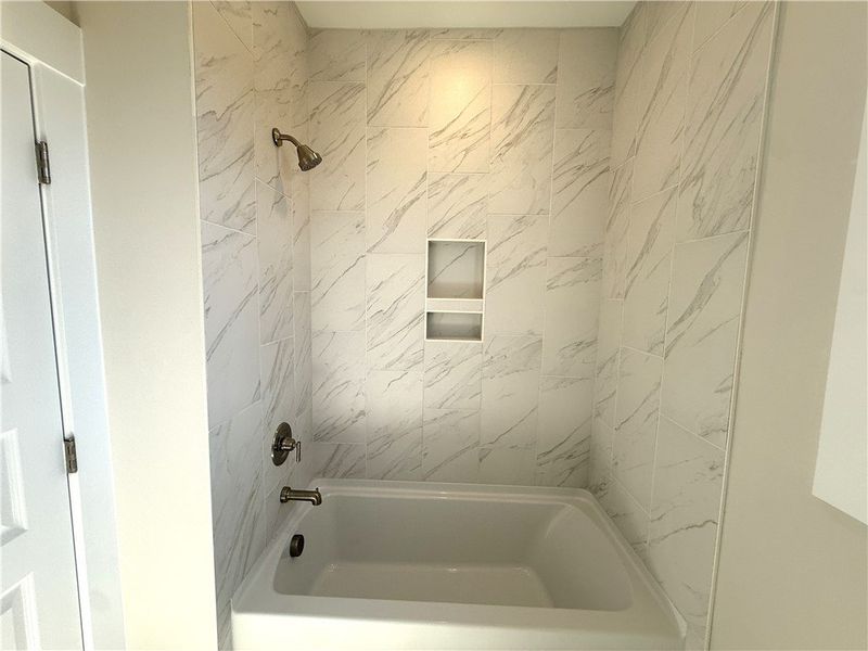 This bathroom features a sleek, tiled shower with