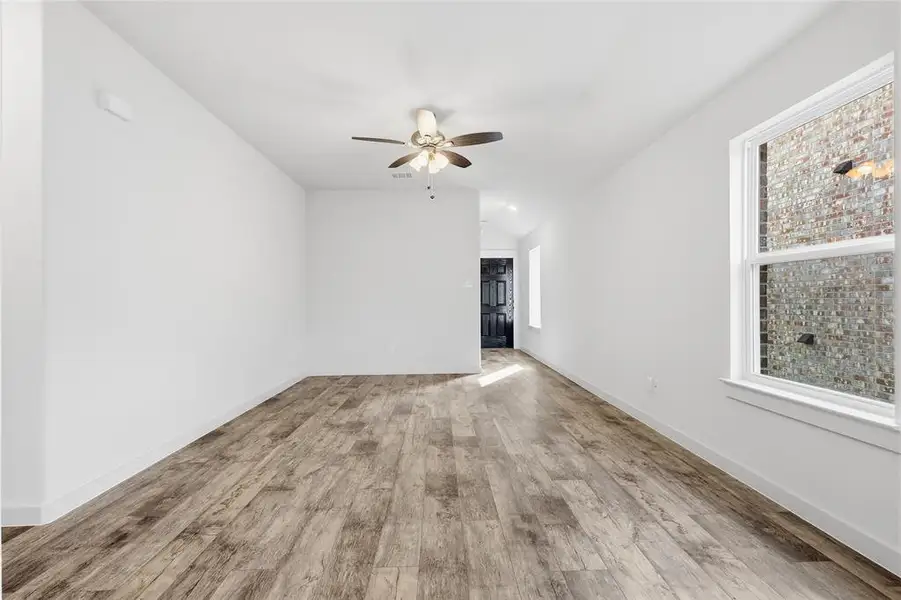 Empty room featuring healthy amount of natural light, light wood-style floors, and a ceiling fan Empty room featuring healthy amount of natural light, light wood-style floors, and a ceiling fan