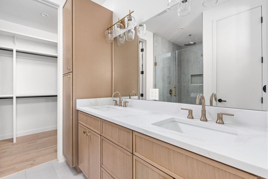 Full bathroom with a stall shower, double vanity, a walk in closet, and tile patterned flooring Full bathroom with a stall shower, double vanity, a walk in closet, and tile patterned flooring