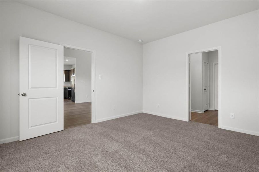 Unfurnished bedroom featuring light colored carpet and stainless steel refrigerator with ice dispenser Unfurnished bedroom featuring light colored carpet and stainless steel refrigerator with ice dispenser