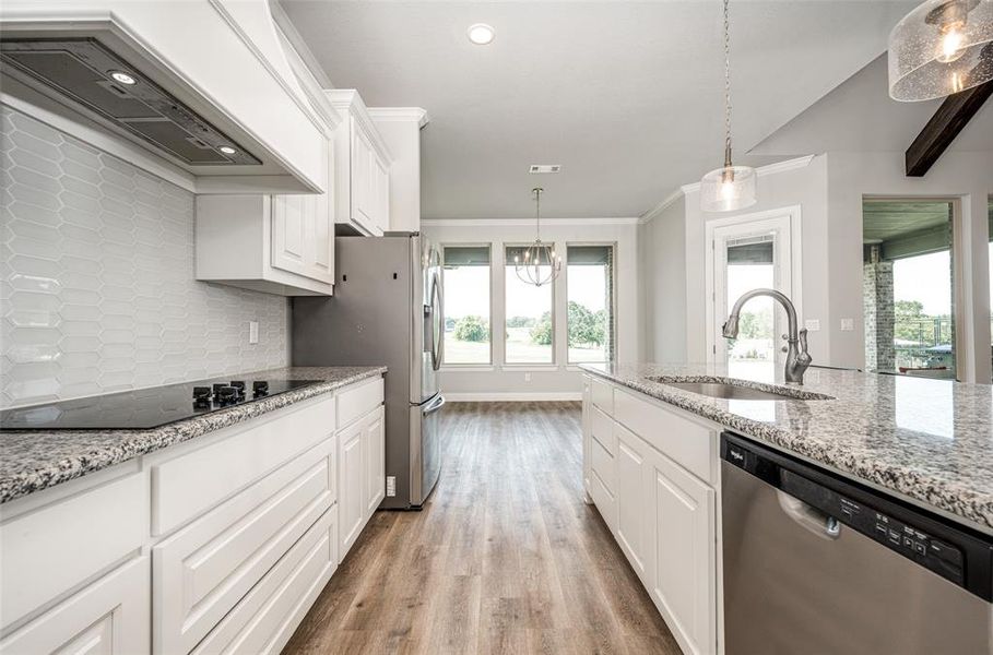 Kitchen featuring custom exhaust hood, stainless steel appliances, white cabinets, light wood-type flooring, and backsplash