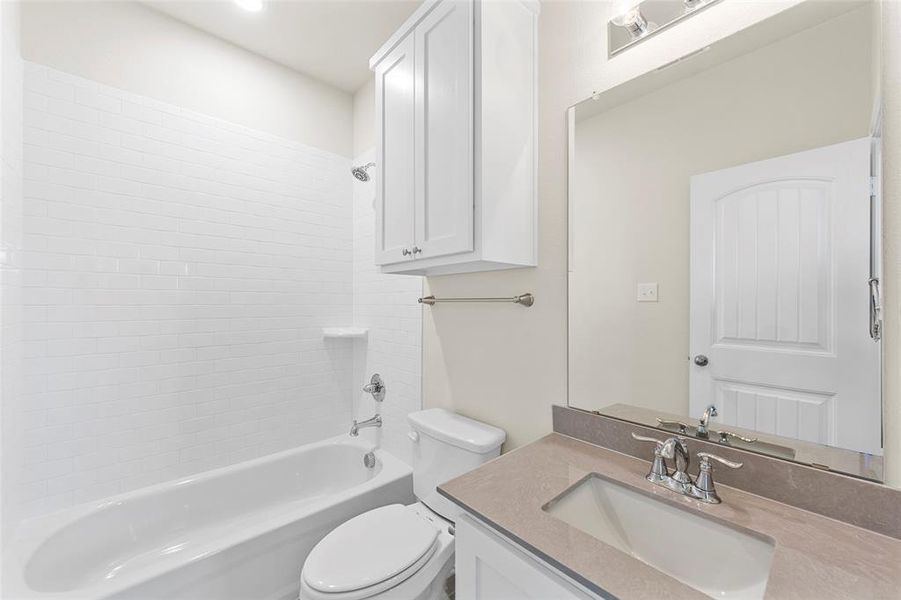 Full bathroom with vanity, tiled shower / bath combo, and toilet