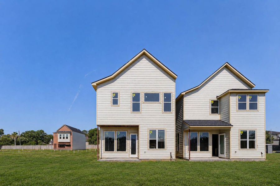 Straight-on rear exterior view showing the paired two-story homes, tall rooflines, rear windows, back doors, and open grassy yard space. This photo highlights the clean architectural style, natural light opportunities, and backyard setting, offering buyers a clear view of the home’s rear elevation and outdoor living potential. Straight-on rear exterior view showing the paired two-story homes, tall rooflines, rear windows, back doors, and open grassy yard space. This photo highlights the clean architectural style, natural light opportunities, and backyard setting, offering buyers a clear view of the home’s rear elevation and outdoor living potential.