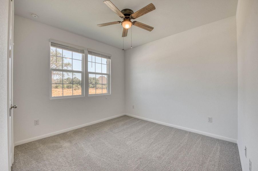 Plush carpeting and dual windows frame quiet neighborhood views in this light-filled room.