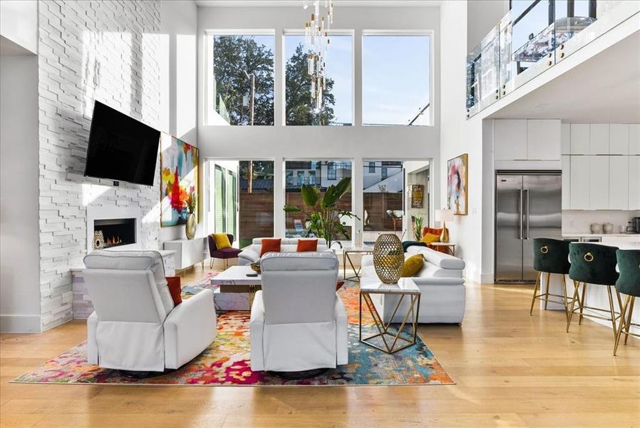 Great room featuring modern linear fireplace with crystals, chandelier, and towering ceilings iwth veiw to the pool oasis